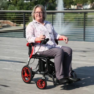 A woman smiling while sitting in a modern wheelchair outdoors by the water.