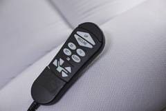 A remote control is sitting on the arm of a couch.
