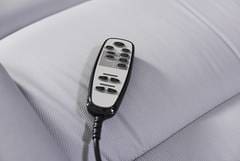 A remote control is attached to the side of a bed.