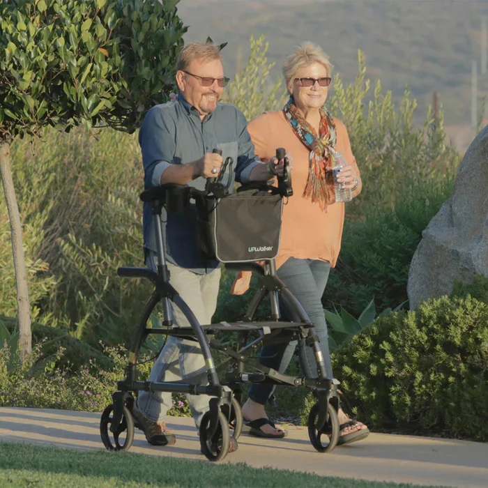 A man and woman are walking with a walker.