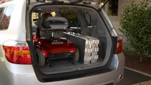Mobility scooter and stacked boxes in a car trunk.