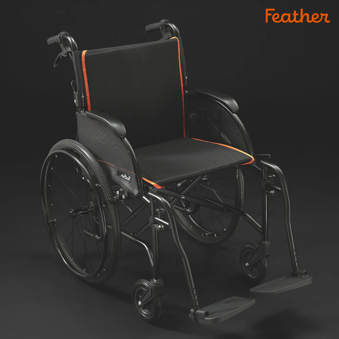 A sleek black wheelchair with orange accents and footrests.