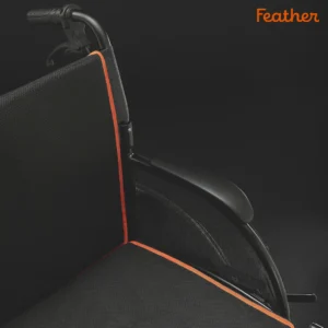Black wheelchair with orange trim against a dark background.