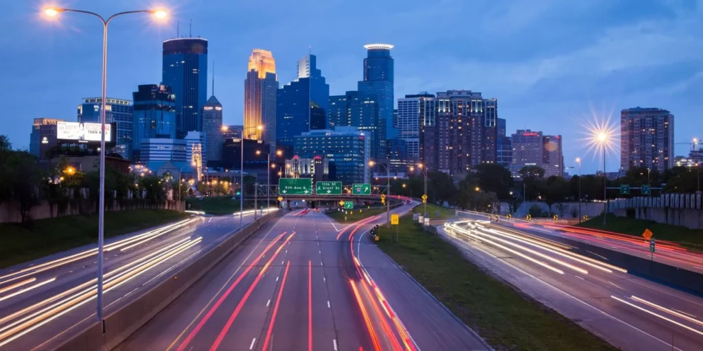 City skyline with light trails from traffic at dusk.