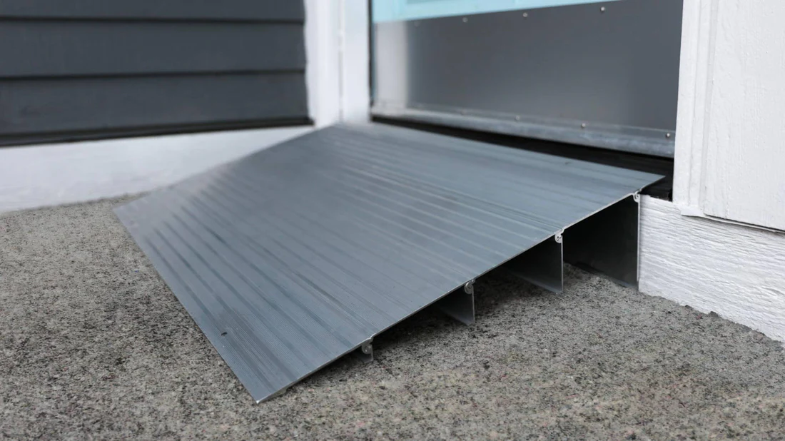 Close-up of a black plastic ramp on the ground near a door.