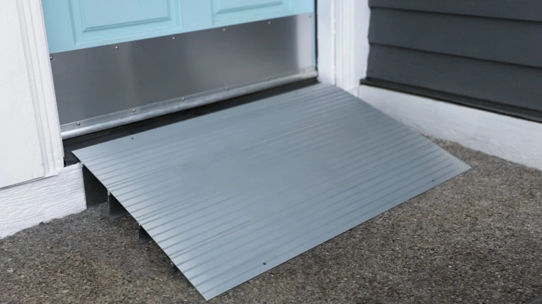 A gray wheelchair ramp placed at a door threshold.