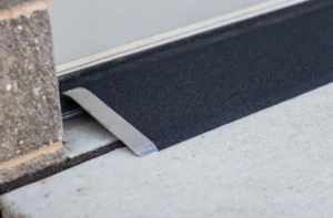 Metal threshold strip securing a black floor mat edge.