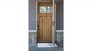 Wooden door with a window and a metal screen on a stone porch.