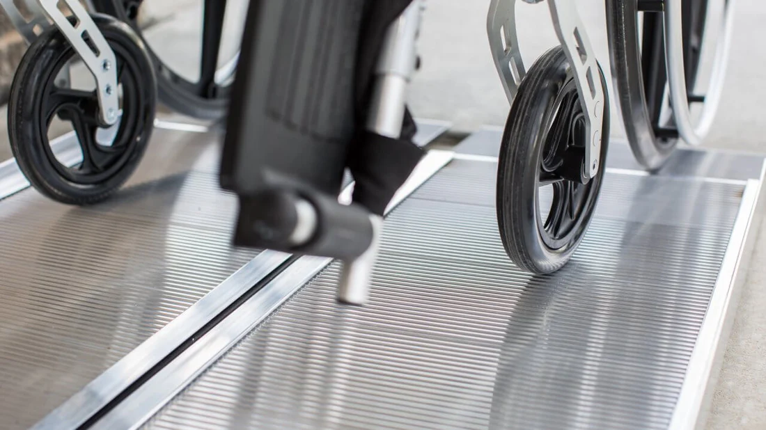 Close-up of a wheelchair wheel on a tiled floor.