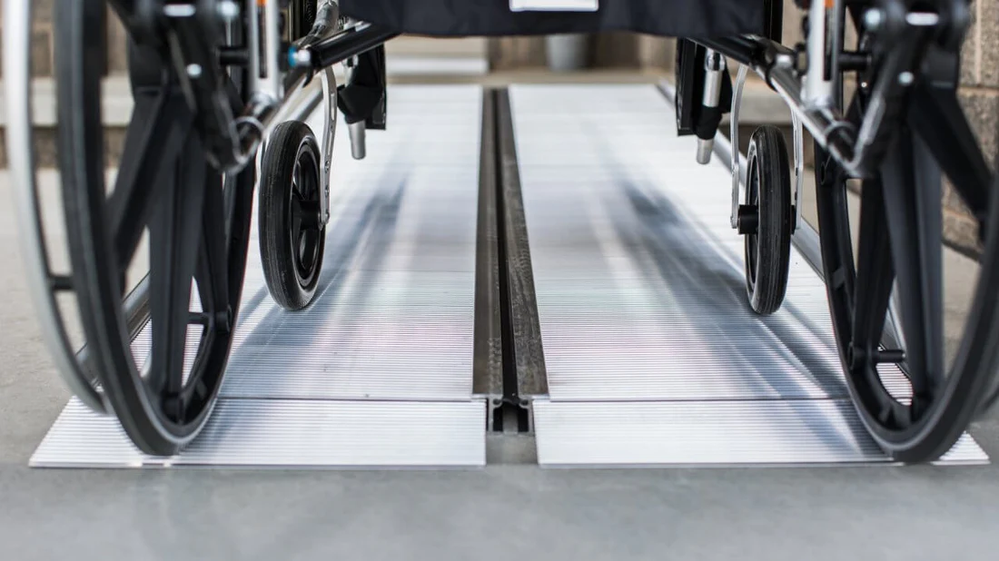 Close-up of wheelchair wheels on a metal track.