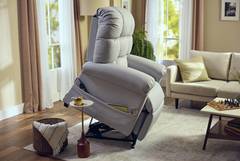 A beige recliner chair with a lifting mechanism in a cozy living room.