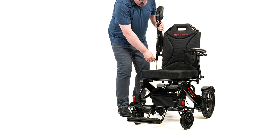 Man assembling a black wheelchair on a white background.