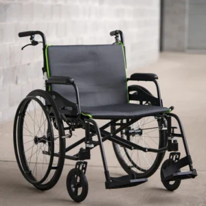 A black wheelchair with green accents on a smooth floor indoors.