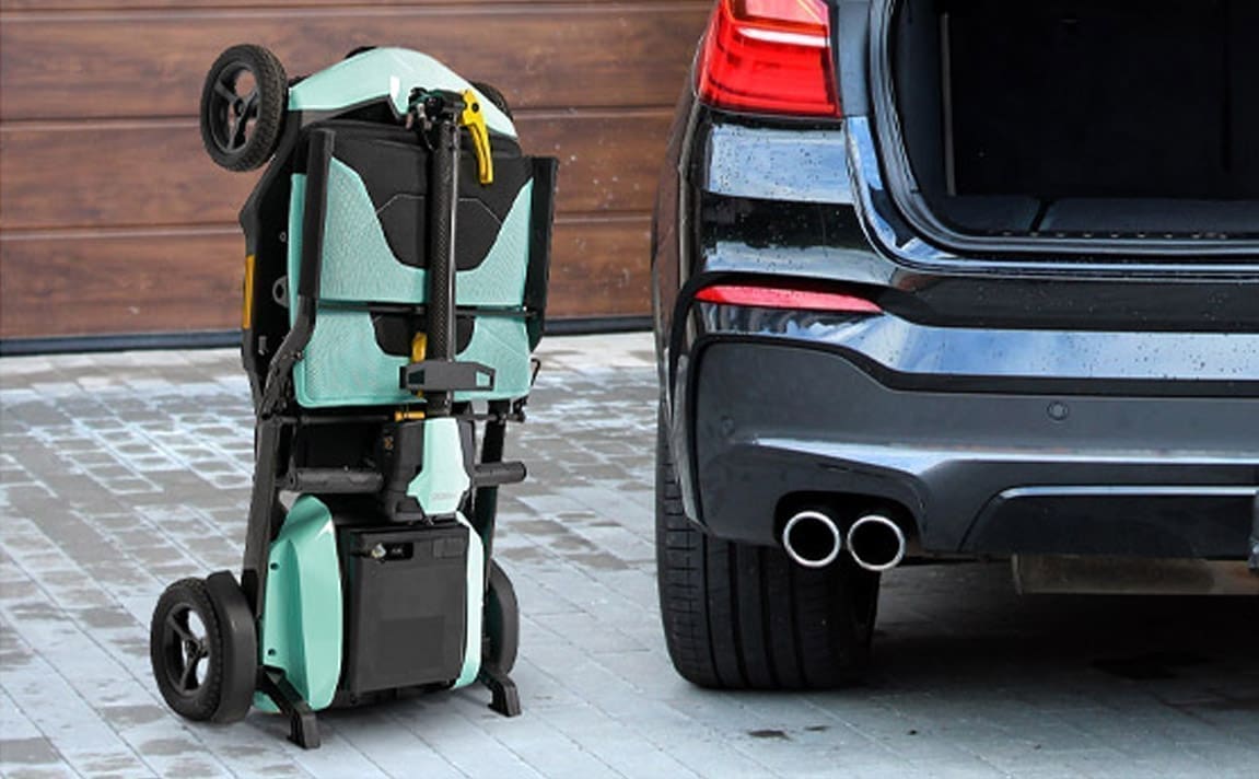 Foldable stroller next to a car with an open trunk.