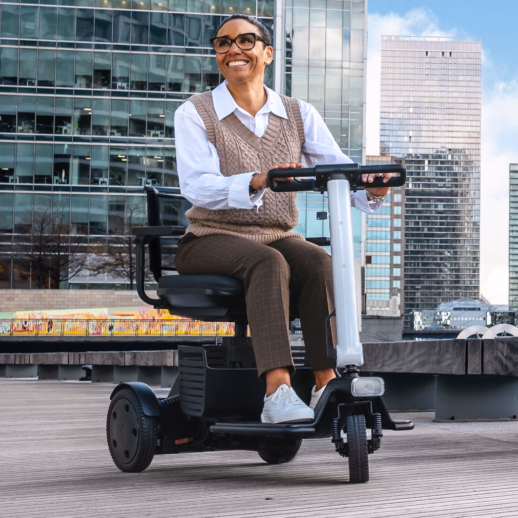 A man in business attire rides an electric scooter in an urban setting.