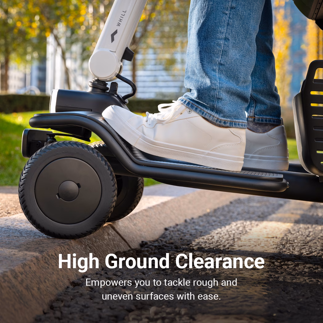 Close-up of a person wearing white sneakers on a scooter with high ground clearance.