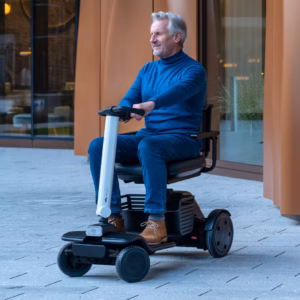 Elderly man riding a mobility scooter outdoors.