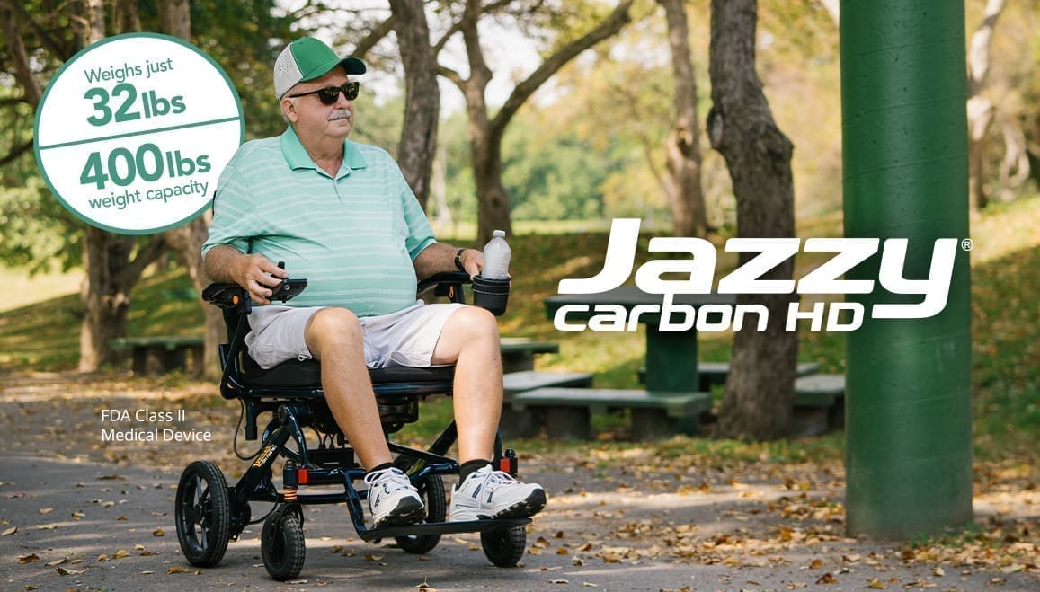 Man enjoying a ride on a Jazzy carbon hybrid mobility scooter in a park.